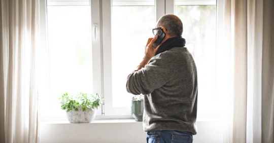 man looking out the window and making a call