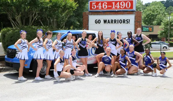 Warriors cheer squad standing around American Pest Control, Inc. truck. American Pest Control is committed to serving the community.
