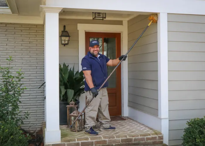 American Pest Control, Inc. technician clears cobwebs from front door of a home in Athens, GA