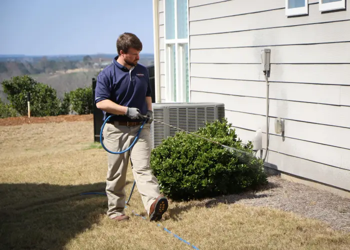 American Pest Control, Inc. technician sprays for pests around the exterior of a home in Athens, GA