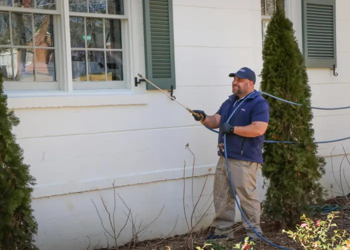 An American Pest Control, Inc. technician sprays along a window to treat a cockroach infestation in Athens, GA
