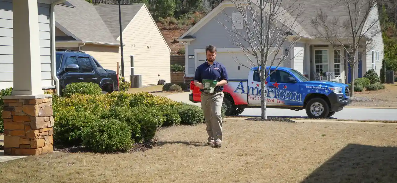 An American Pest Control, Inc. technician spreads granular insecticide around an Athens, GA home to control ticks