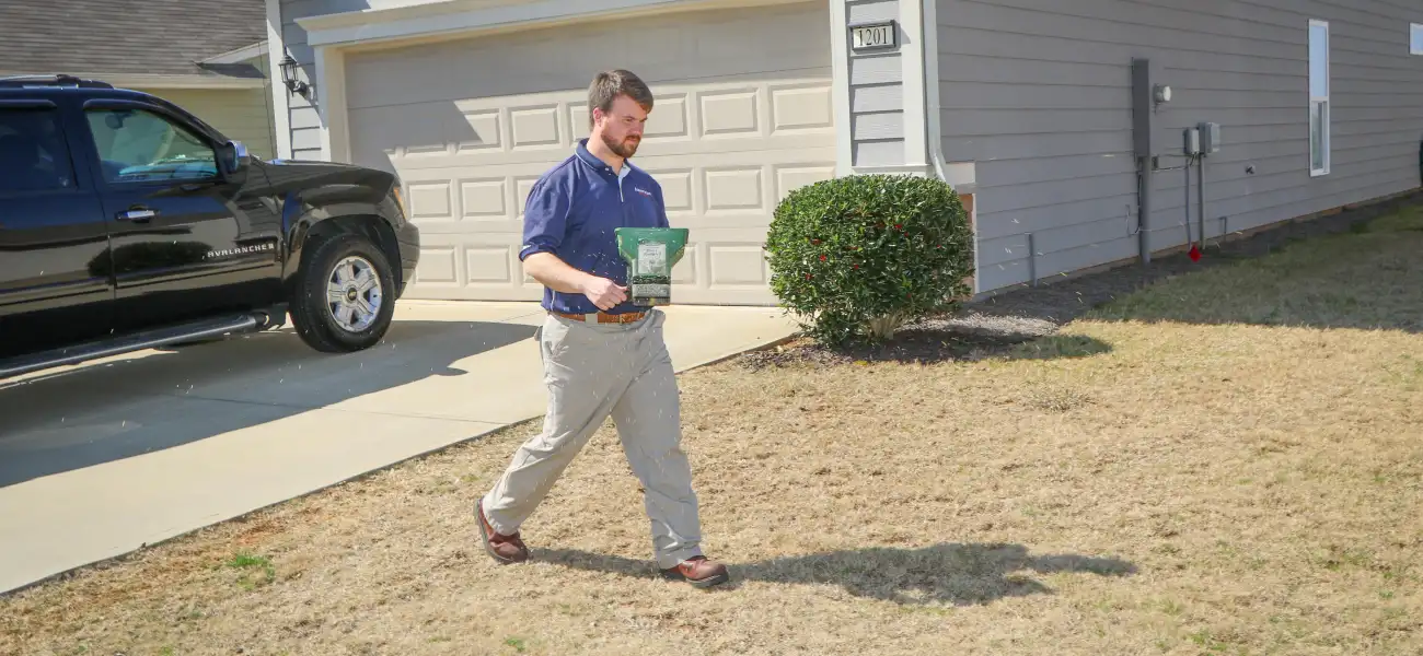 An American Pest Control, Inc. technician applying granular treatment to an Athens, GA yard to treat crickets and other unwanted pests