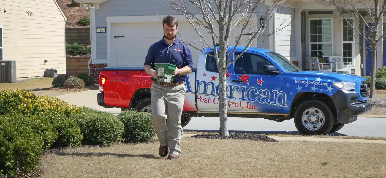 An American Pest Control, Inc. technician applying flea treatment to a yard in Athens, GA
