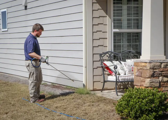 An American Pest Control, Inc. technician sprays around an Athens, GA home for ticks