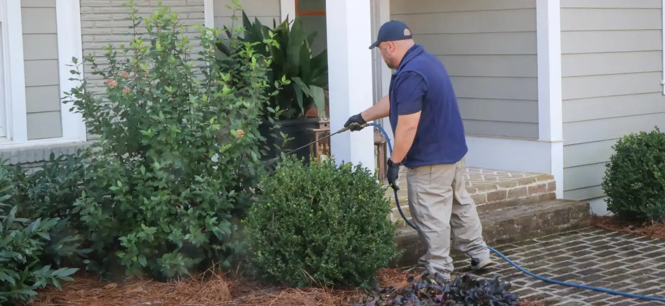 An American Pest Control, Inc. technician applying liquid pest treatment to the exterior of an Athens, GA home