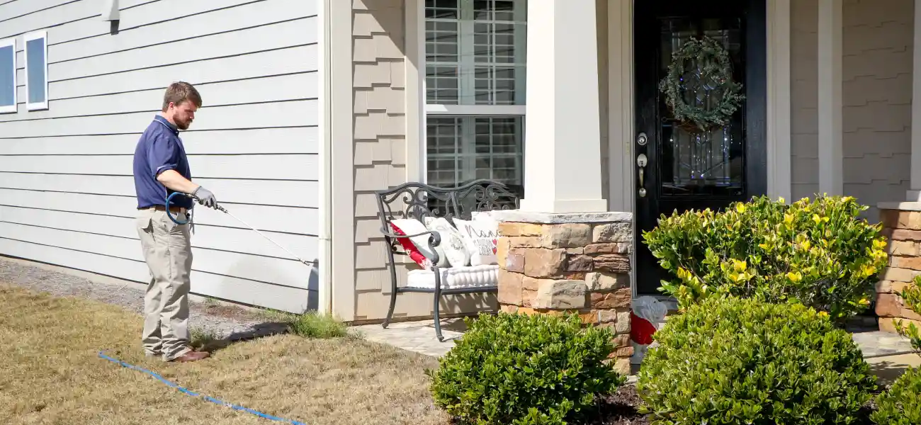 An American Pest Control, Inc. technician sprays the outer perimeter of an Athens, GA home for cockroaches