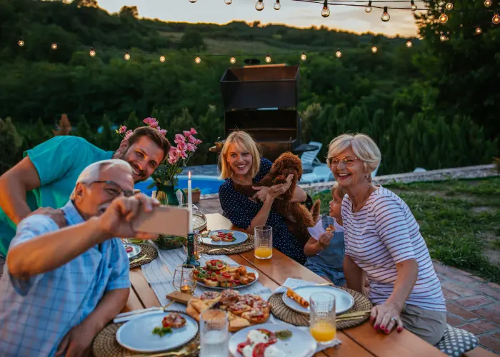 A family taking a picture in their backyard while eating dinner after mosquito treatment. Take back your yard with a mosquito protection plan from American Pest Control, Inc.