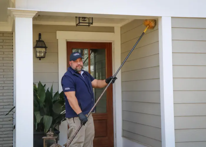 An American Pest Control, Inc. technician removes cobwebs from an Athens, GA home as part of a 5-Star Protection Plan