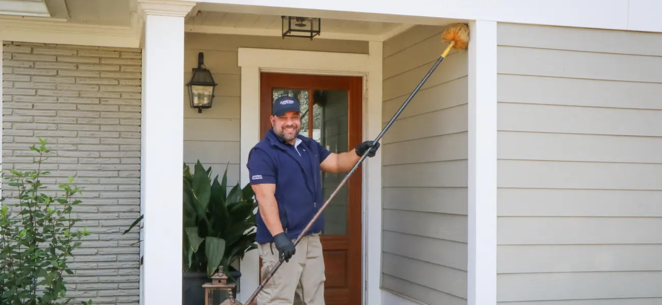 An American Pest Control, Inc. technician removes spider webs from a home in Athens, GA