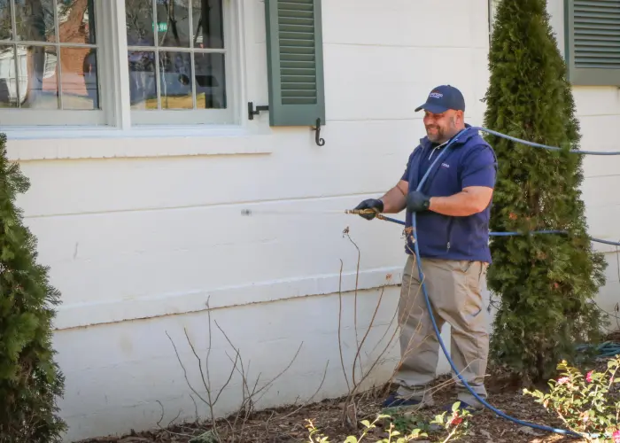 An American Pest Control, Inc. technician applying liquid termite treatment to an Athens, GA home