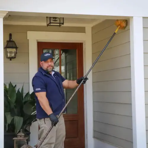 An American Pest Control, Inc. technician removes cobwebs from a residential home